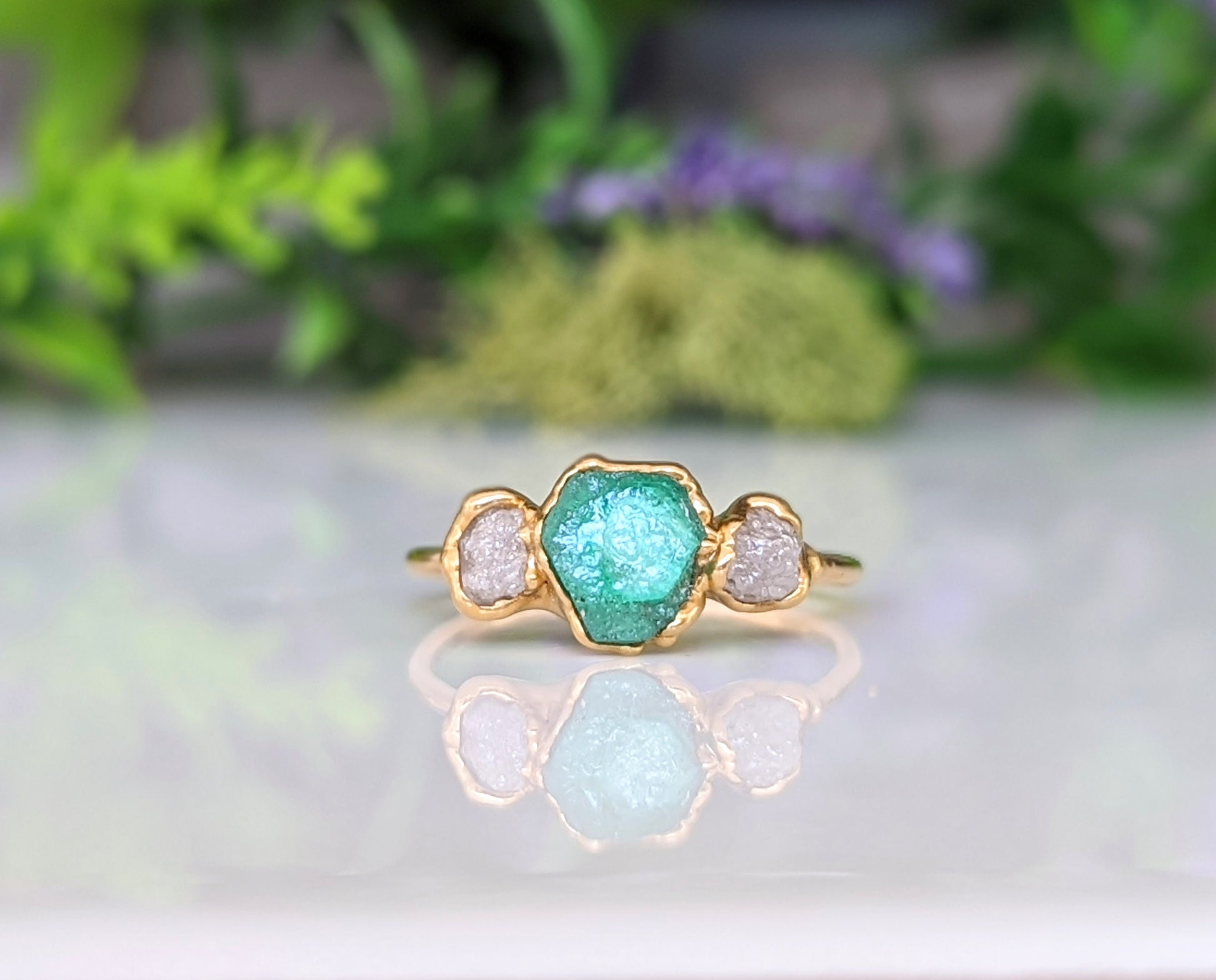 Handcrafted raw emerald and diamond engagement ring with gold band, symbolizing love and commitment.