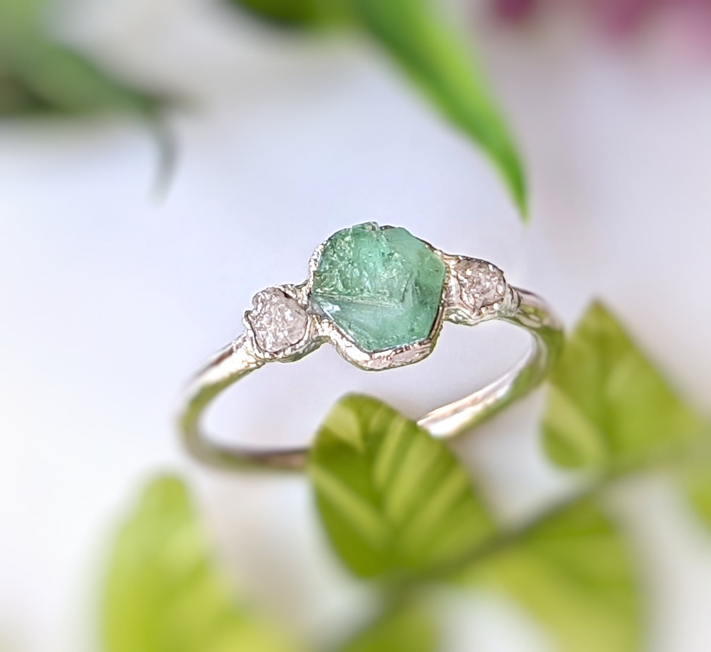Handcrafted raw emerald and diamond engagement ring, symbolizing love and commitment with rustic elegance.