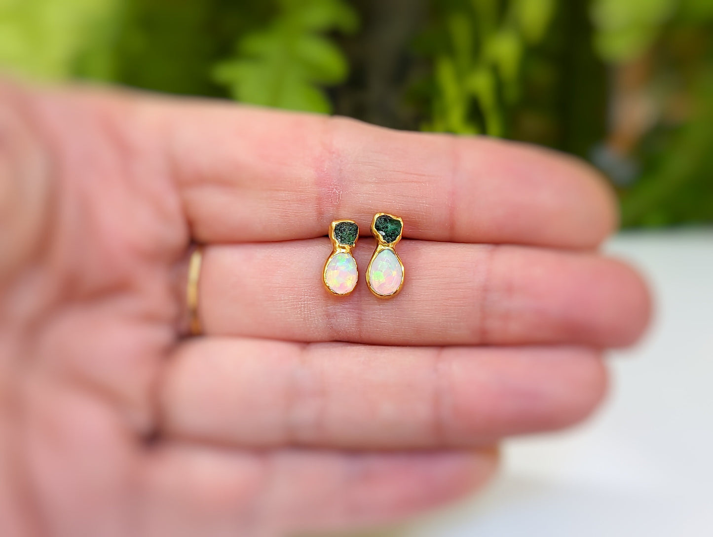 Handcrafted raw Emerald and Opal stud earrings displayed on a hand, showcasing their unique and elegant design.