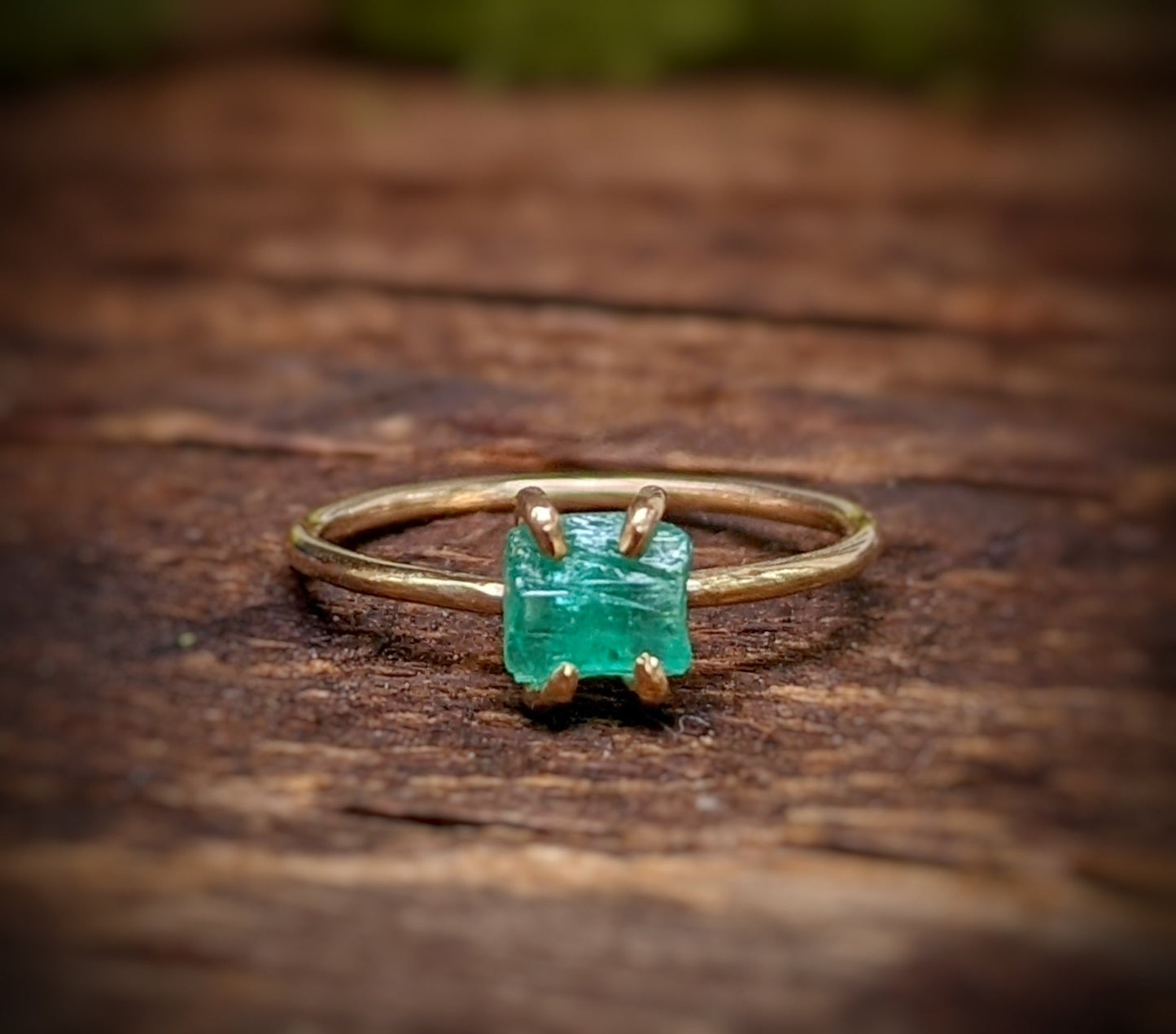 Raw emerald solitaire ring in solid 14k gold, showcasing unique green gem on a rustic band.