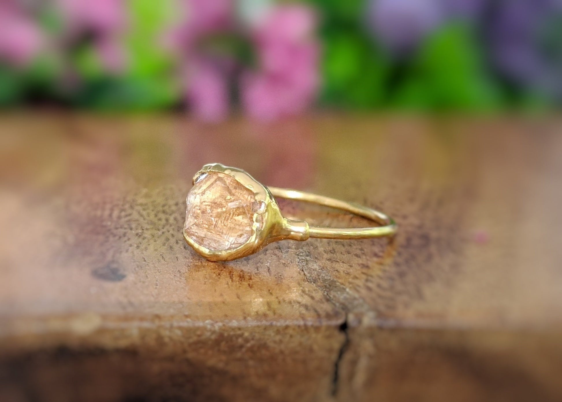 Raw Hessonite Garnet ring on a wooden surface, featuring an 18k Gold plated band and a unique golden gemstone.
