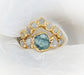 Raw Montana Sapphire and diamond bridal ring set in gold, featuring a teal blue sapphire with sparkling diamonds.