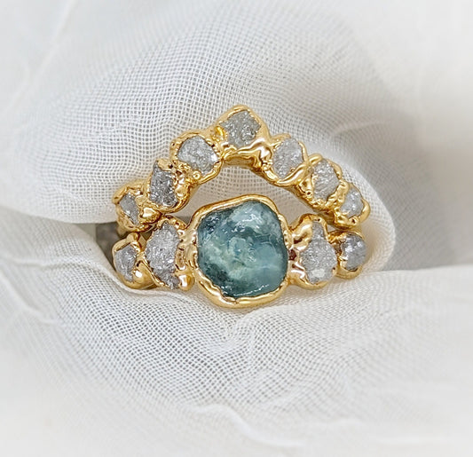 Raw Montana Sapphire and diamond ring set in 14k gold on a soft fabric background, symbolizing unique love.