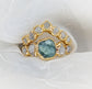 Raw Montana Sapphire and diamond ring set in 14k gold on a soft fabric background, symbolizing unique love.