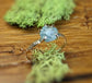 Raw Montana Sapphire ring with textured gold band against natural moss background.