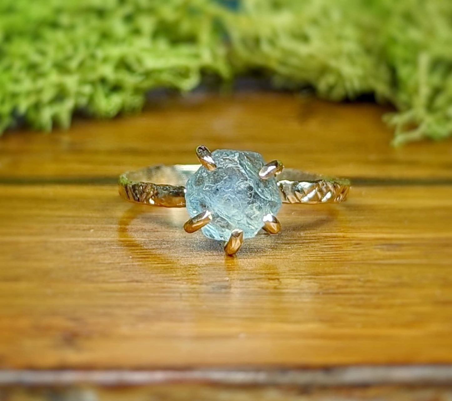 Raw Montana Sapphire ring with a textured gold band, showcasing teal-blue hues and rustic elegance.