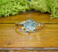 Raw Montana Sapphire ring with a textured gold band, showcasing teal-blue hues and rustic elegance.