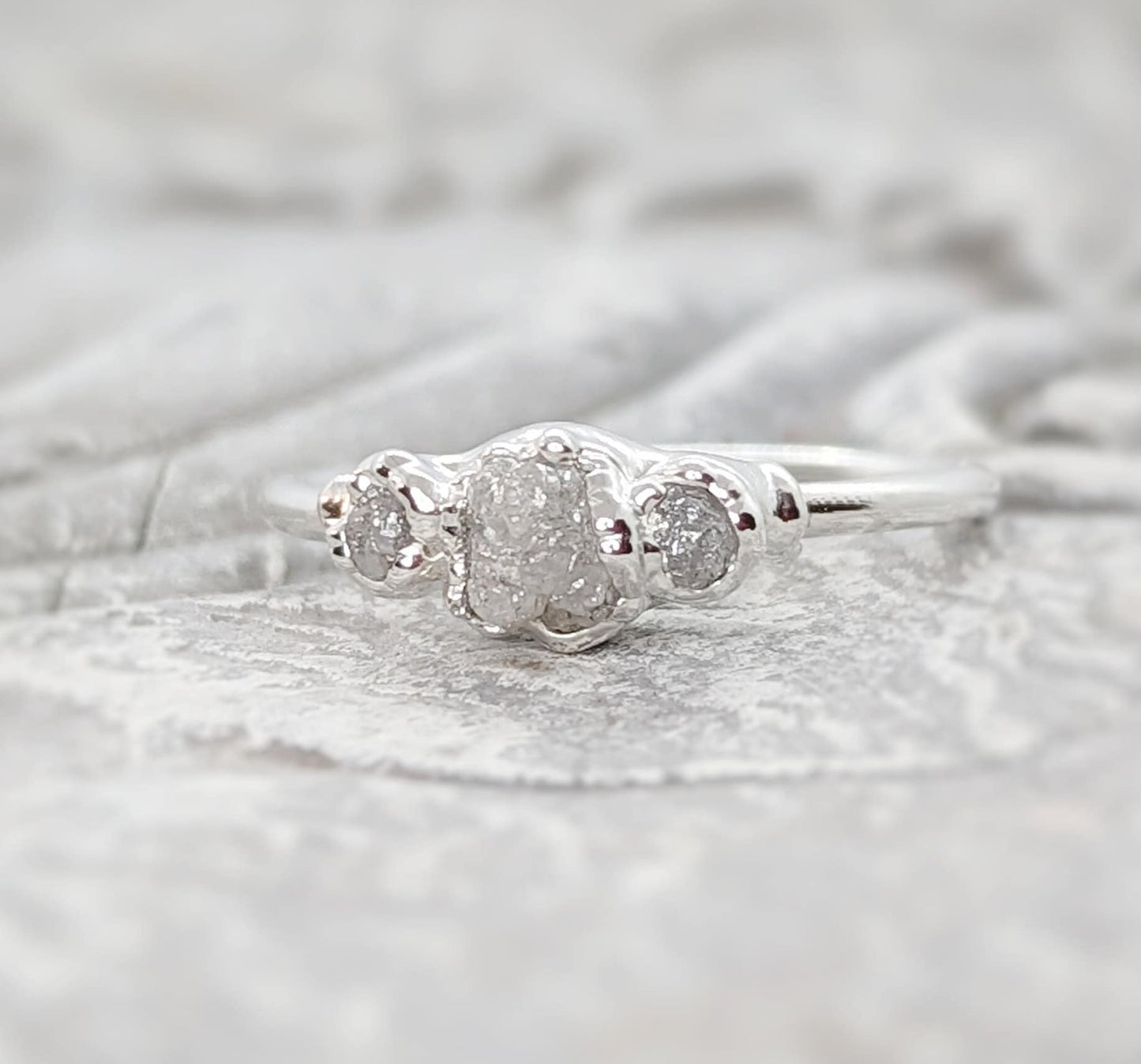 Handcrafted raw diamond engagement ring with one large and two smaller raw diamonds, set in silver.