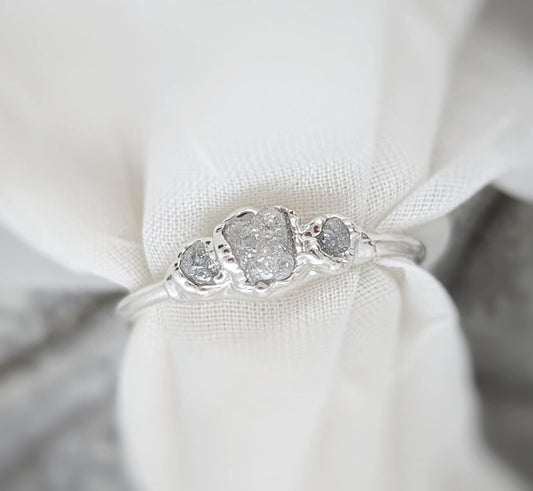 Handcrafted raw diamond engagement ring with sparkling center diamond and two smaller diamonds, set in silver.
