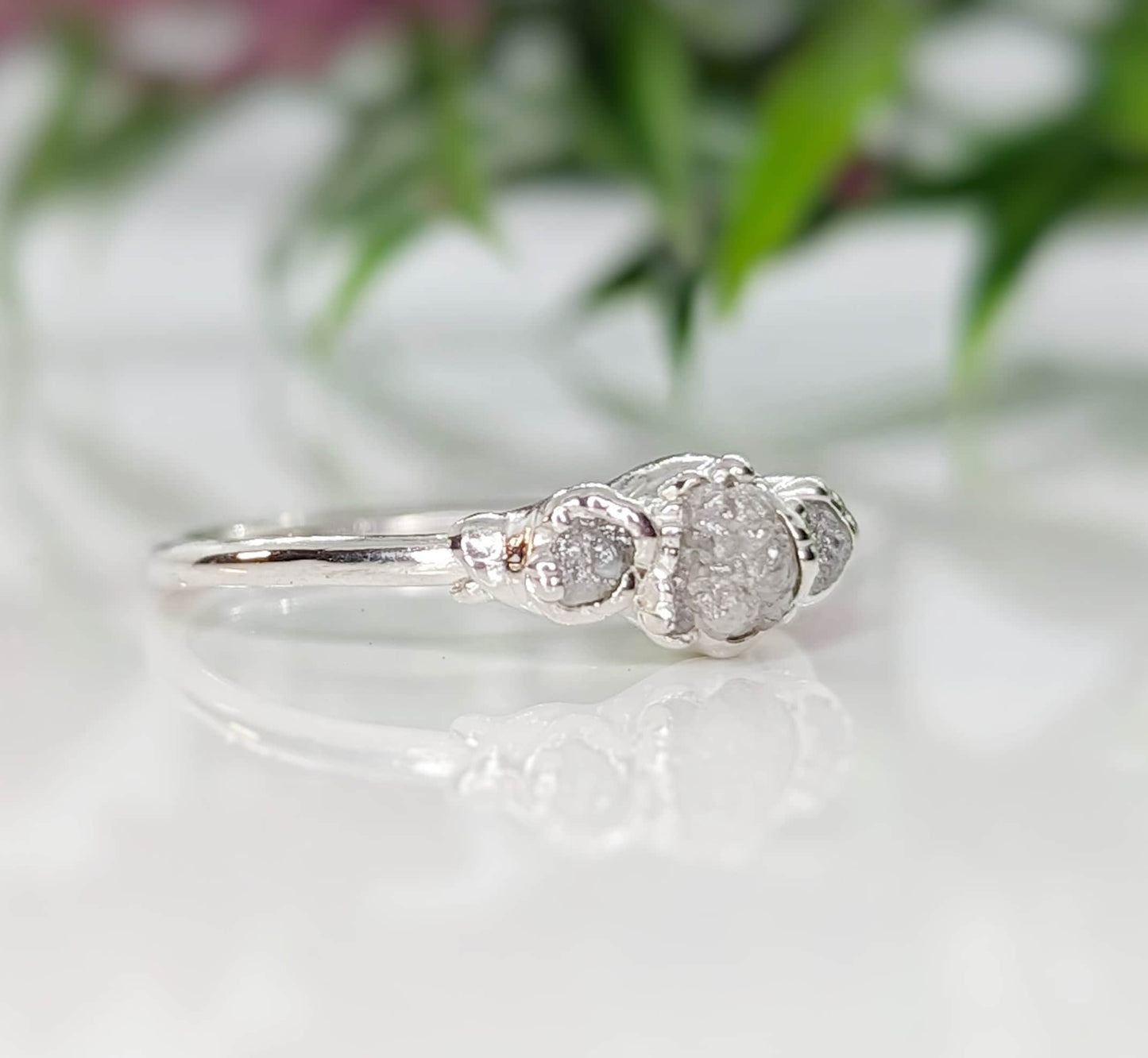 Handcrafted raw diamond engagement ring with a central raw diamond and two smaller side diamonds, showcasing unique elegance.
