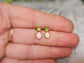 Dainty handcrafted raw Peridot and Opal stud earrings displayed in a hand, perfect for gifts and special occasions.