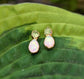Dainty raw Peridot and Opal stud earrings nestled on green leaves, showcasing unique handcrafted design.