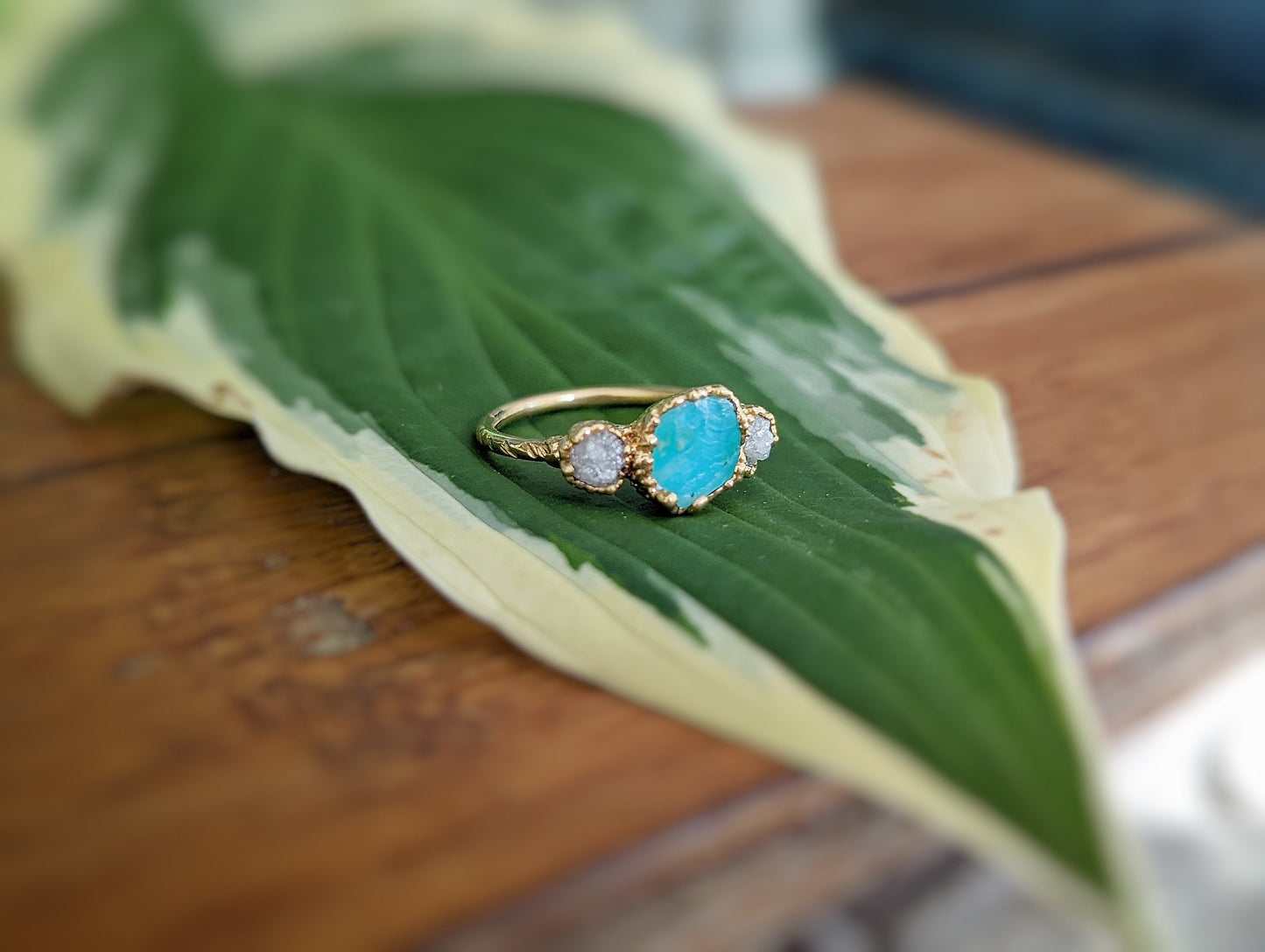 Raw Peruvian Opal and diamond ring set on a green leaf, showcasing its unique 14k gold design.