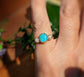 Raw Peruvian Opal and diamond ring in solid 14k gold, featured on hand with floral background.