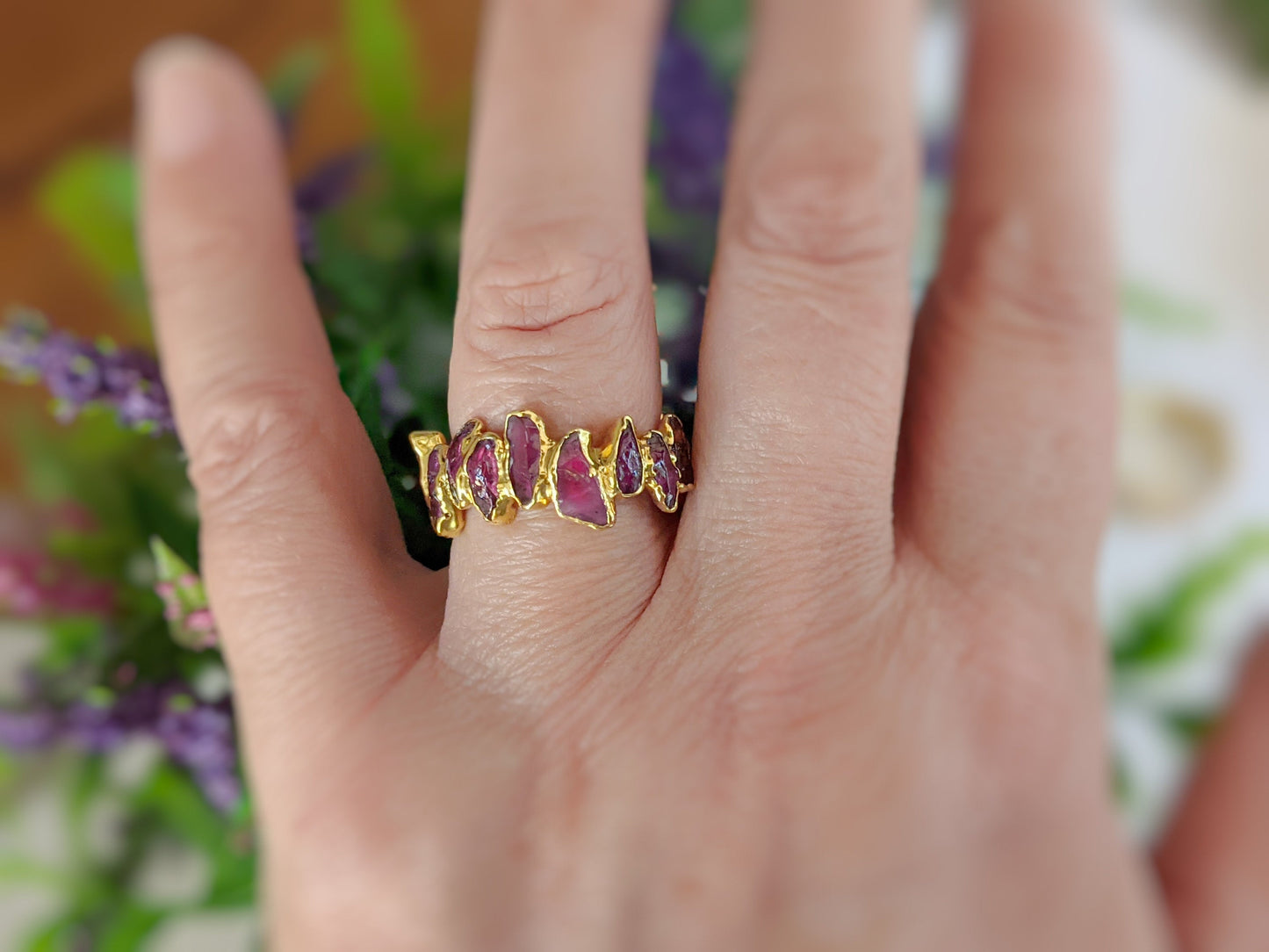 Hand wearing a Raw Rhodolite Garnet Eternity Ring with a gold filled 14k band, showcasing vibrant gemstones.