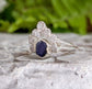 Raw sapphire and diamond wedding ring set on a stone surface, featuring a stylish Sterling Silver band.