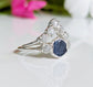 Raw sapphire and diamond wedding ring set on a reflective surface, featuring a unique design with conflict-free diamonds.