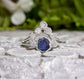 Raw sapphire and diamond wedding ring set on a stone surface, featuring a unique design in sterling silver.