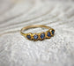 Raw sapphire multi-stone ring on a textured surface, featuring small blue sapphires set in a solid gold band.