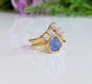 Raw Tanzanite and diamond Chevron wedding ring set on a gold band, featuring a stunning purple crystal design.