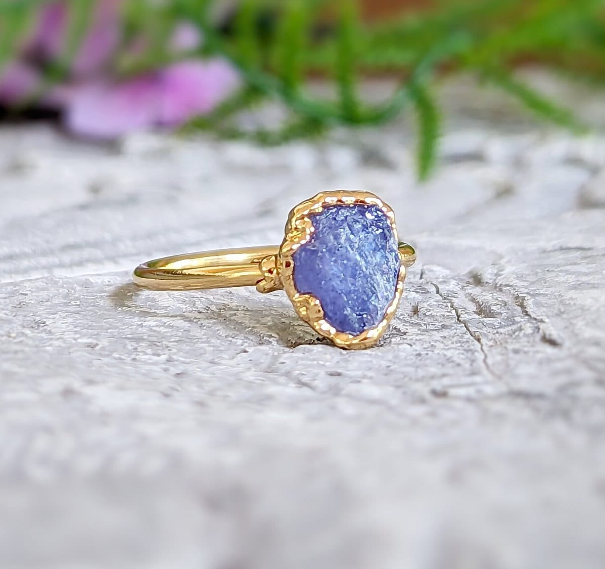 Raw Tanzanite ring set in 14k gold-filled band, showcasing a unique purple gemstone design on a rustic surface.
