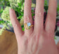 Close-up of a raw gemstone cluster ring featuring golden imperial topaz, aquamarine, and peridot on a hand.