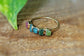 Colorful raw Tourmaline eternity ring on a wooden surface, featuring five multi-color stones set on a gold band.