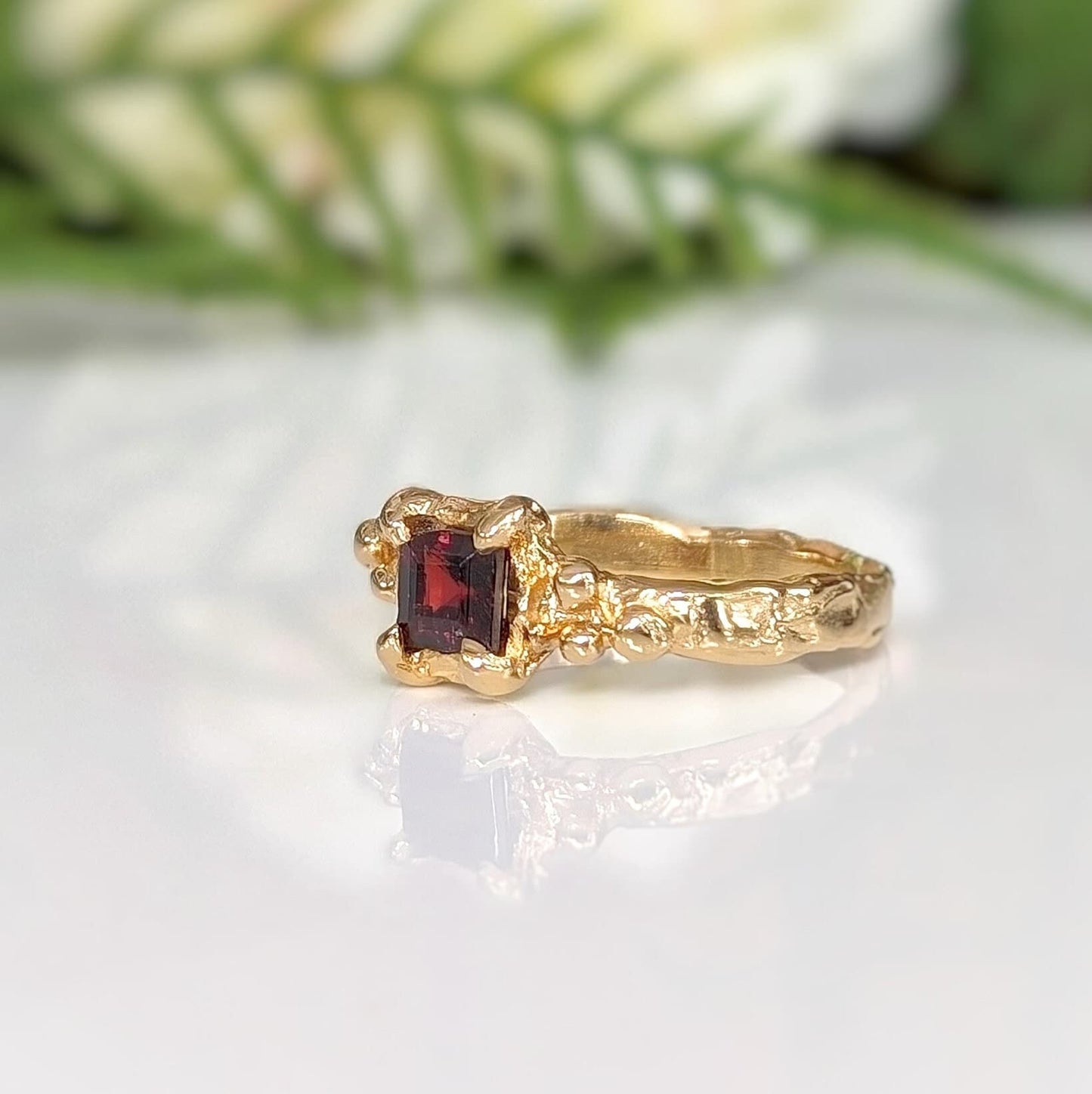 Red Garnet engagement ring in solid 14k gold with organic textured band, showcasing a square cut crystal.