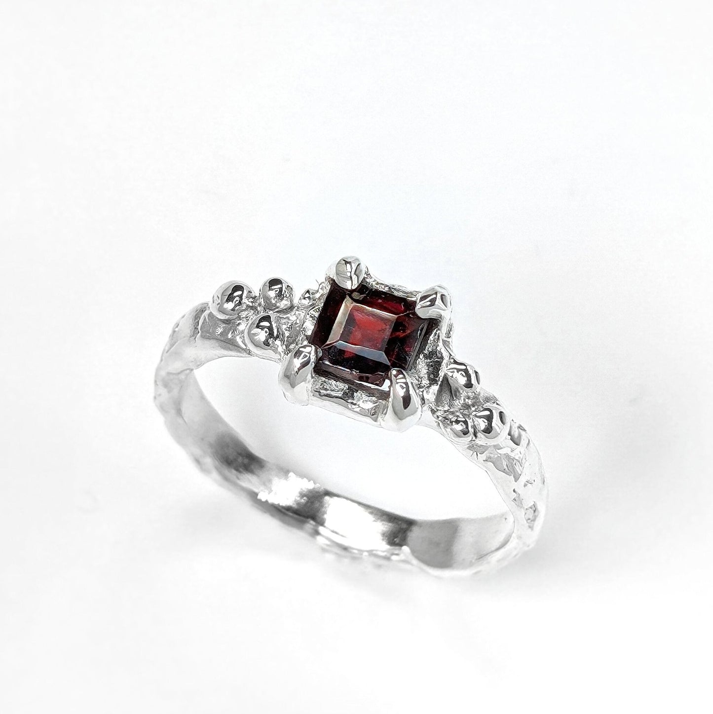 Red Garnet engagement ring in solid sterling silver with an organic textured band and square cut garnet gemstone.
