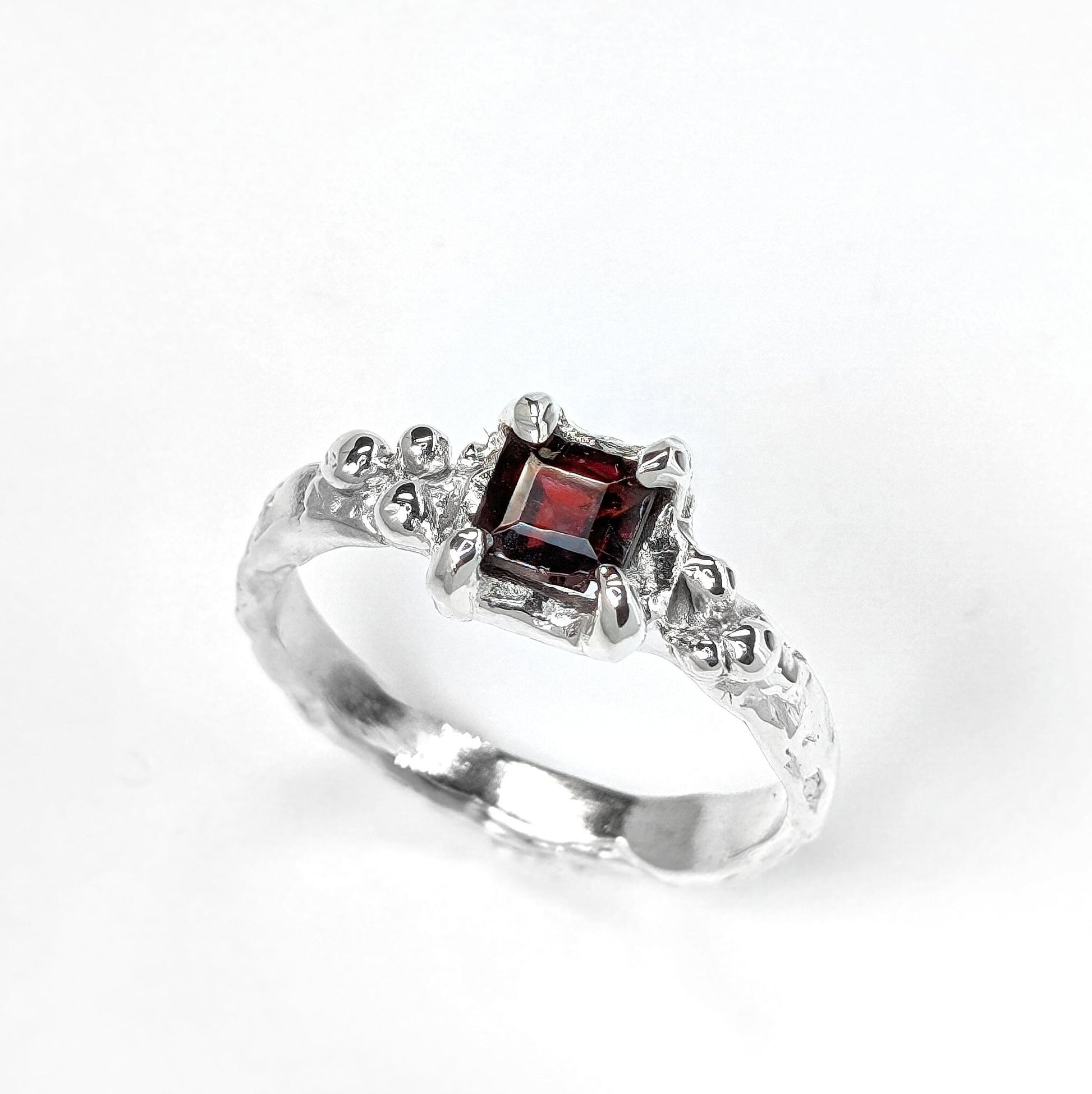 Red Garnet engagement ring in solid sterling silver with an organic textured band and square cut garnet gemstone.