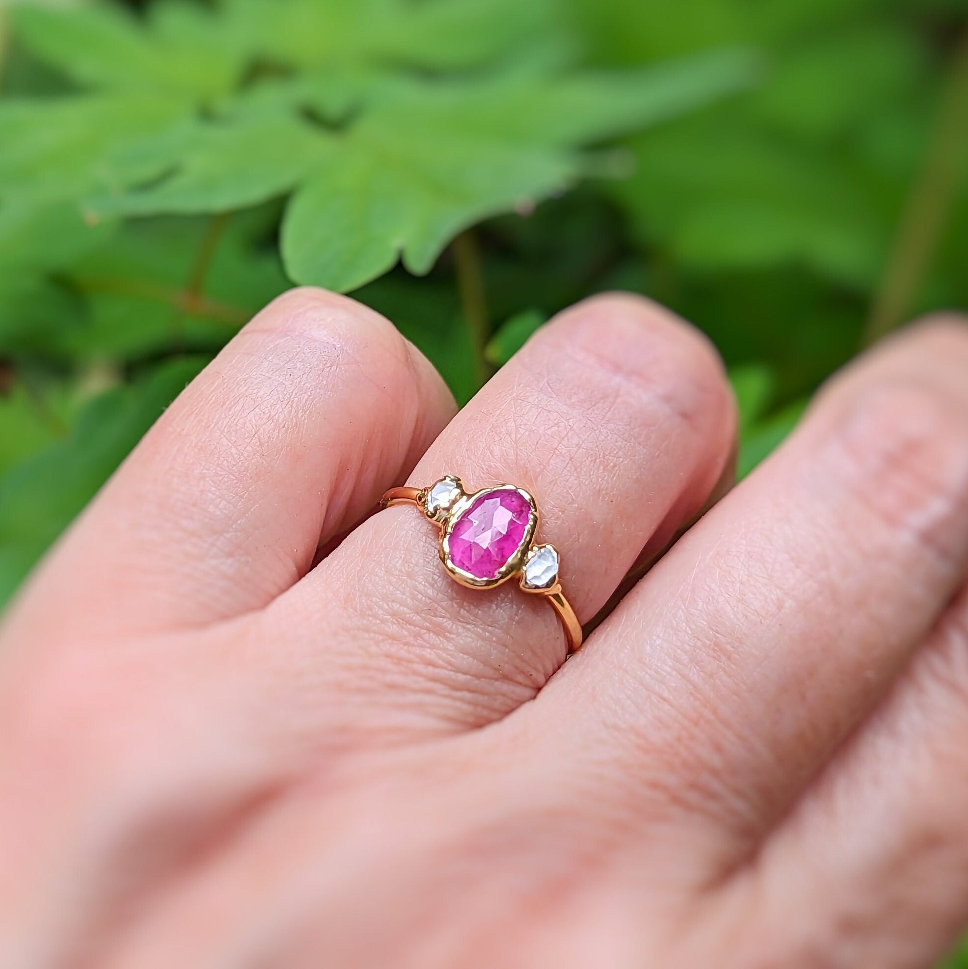 Handcrafted Rubellite Tourmaline engagement ring with diamonds on a 14k gold band, showcased on a hand.