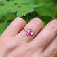 Handcrafted Rubellite Tourmaline engagement ring with diamonds on a 14k gold band, showcased on a hand.