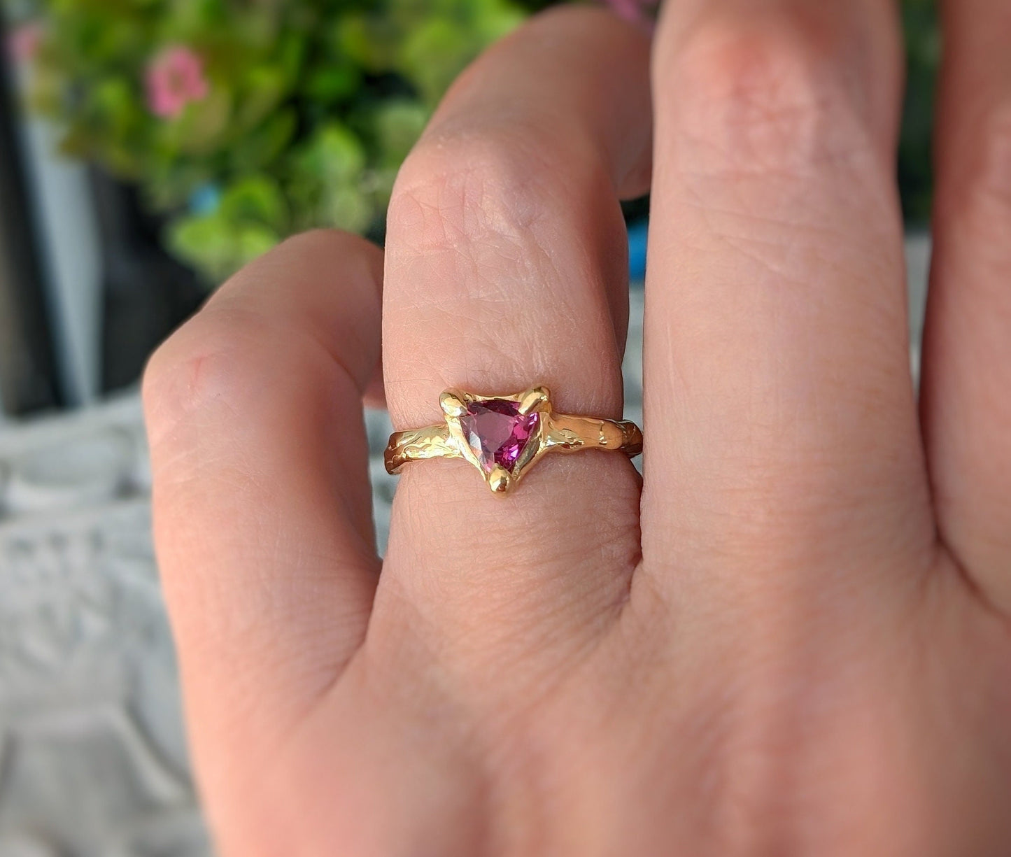Hand wearing a Rubellite Tourmaline engagement ring in solid 14k gold with a trilliant cut gem.