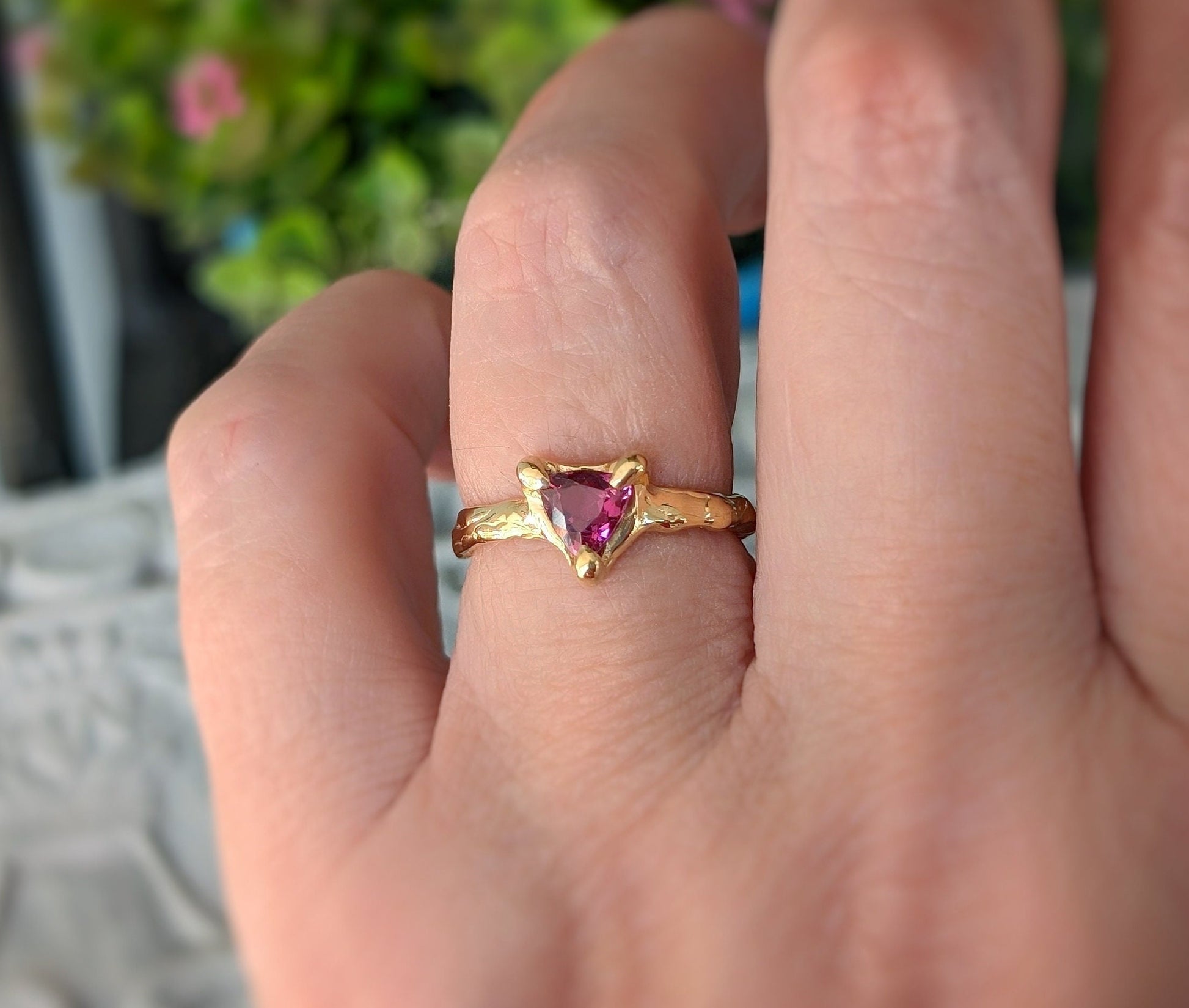 Hand wearing a Rubellite Tourmaline engagement ring in solid 14k gold with a trilliant cut gem.