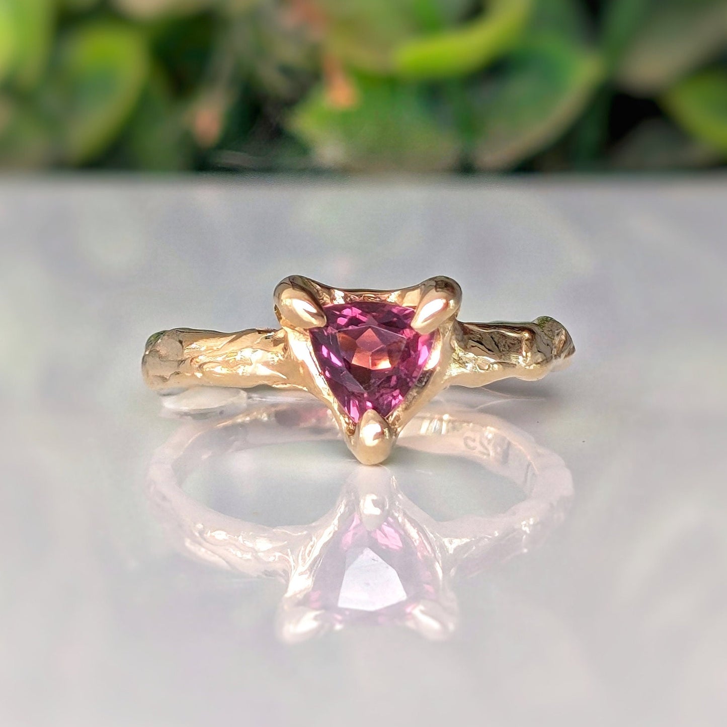 Rubellite tourmaline engagement ring in solid 14k gold with organic textured band and trilliant cut gemstone.