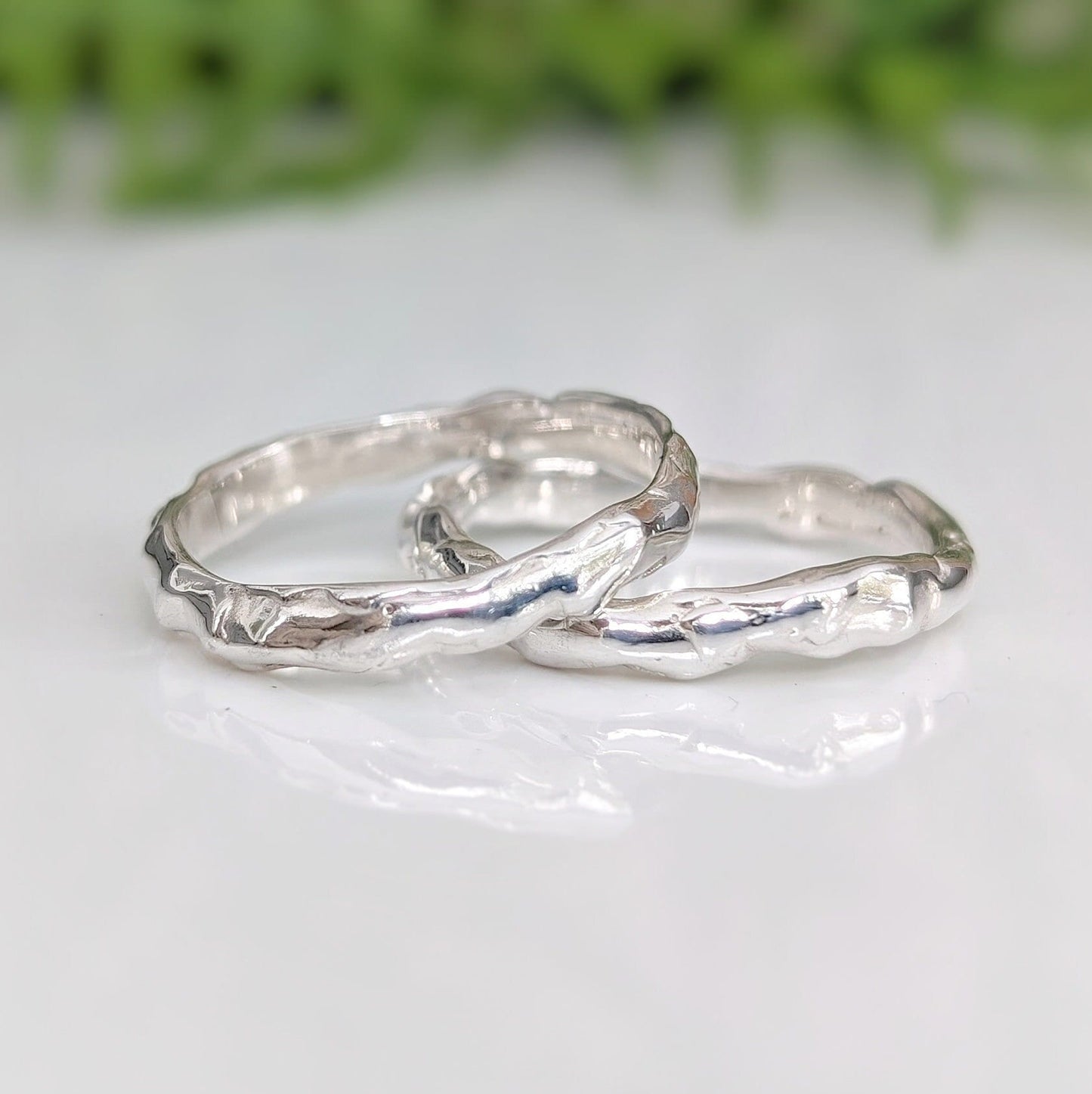 Two handcrafted Molten Silver wedding bands showcasing unique abstract designs and a nature-inspired texture.
