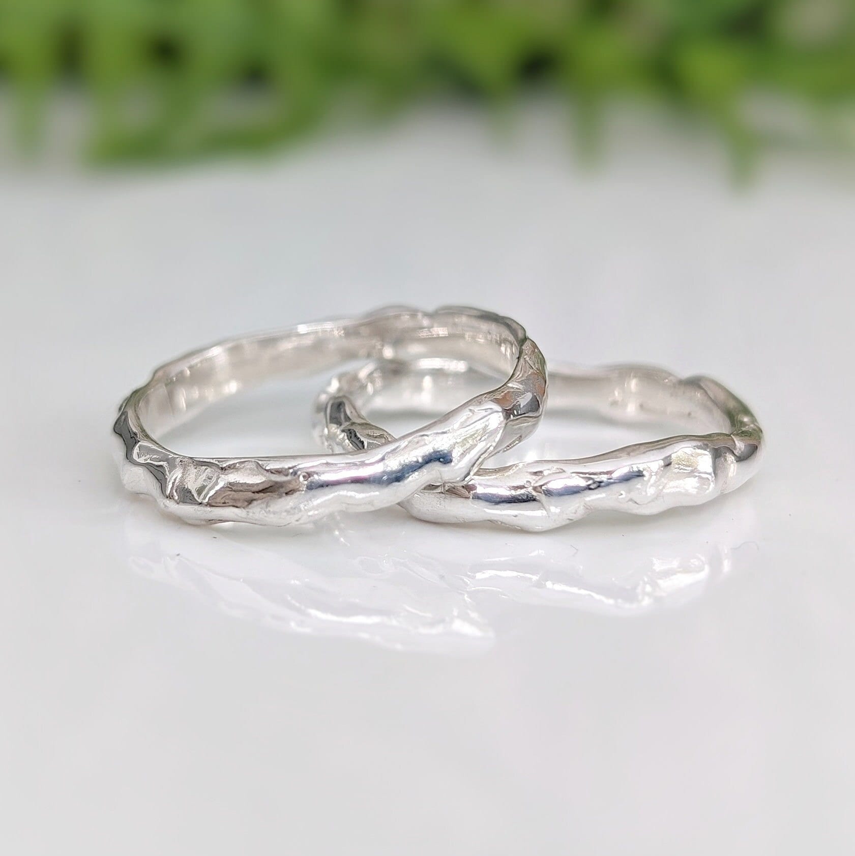 Two handcrafted Molten Silver wedding bands showcasing unique abstract designs and a nature-inspired texture.