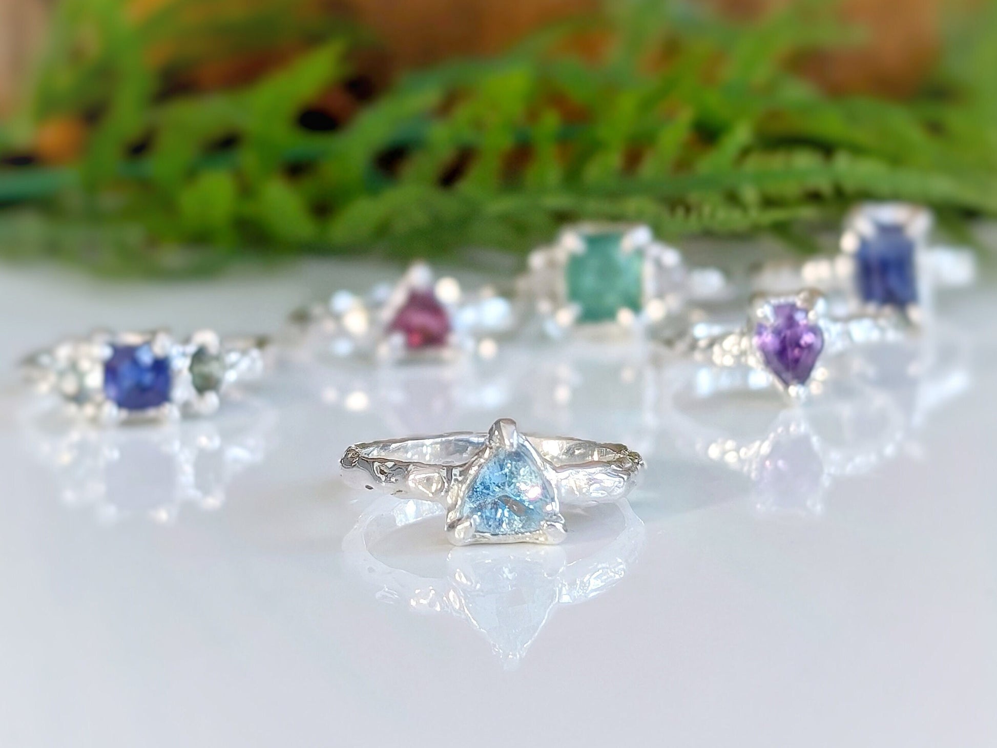 Solid silver aquamarine ring with trilliant gem, showcased among other colorful gemstone rings.