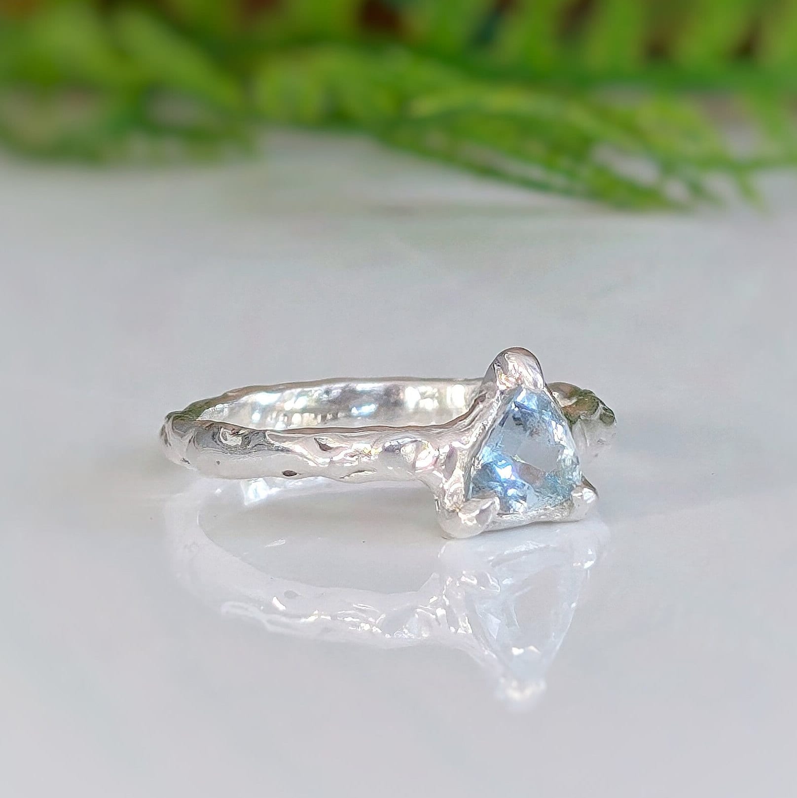 Solid Silver Aquamarine ring with trilliant shape stone on textured band, reflecting love and individuality.