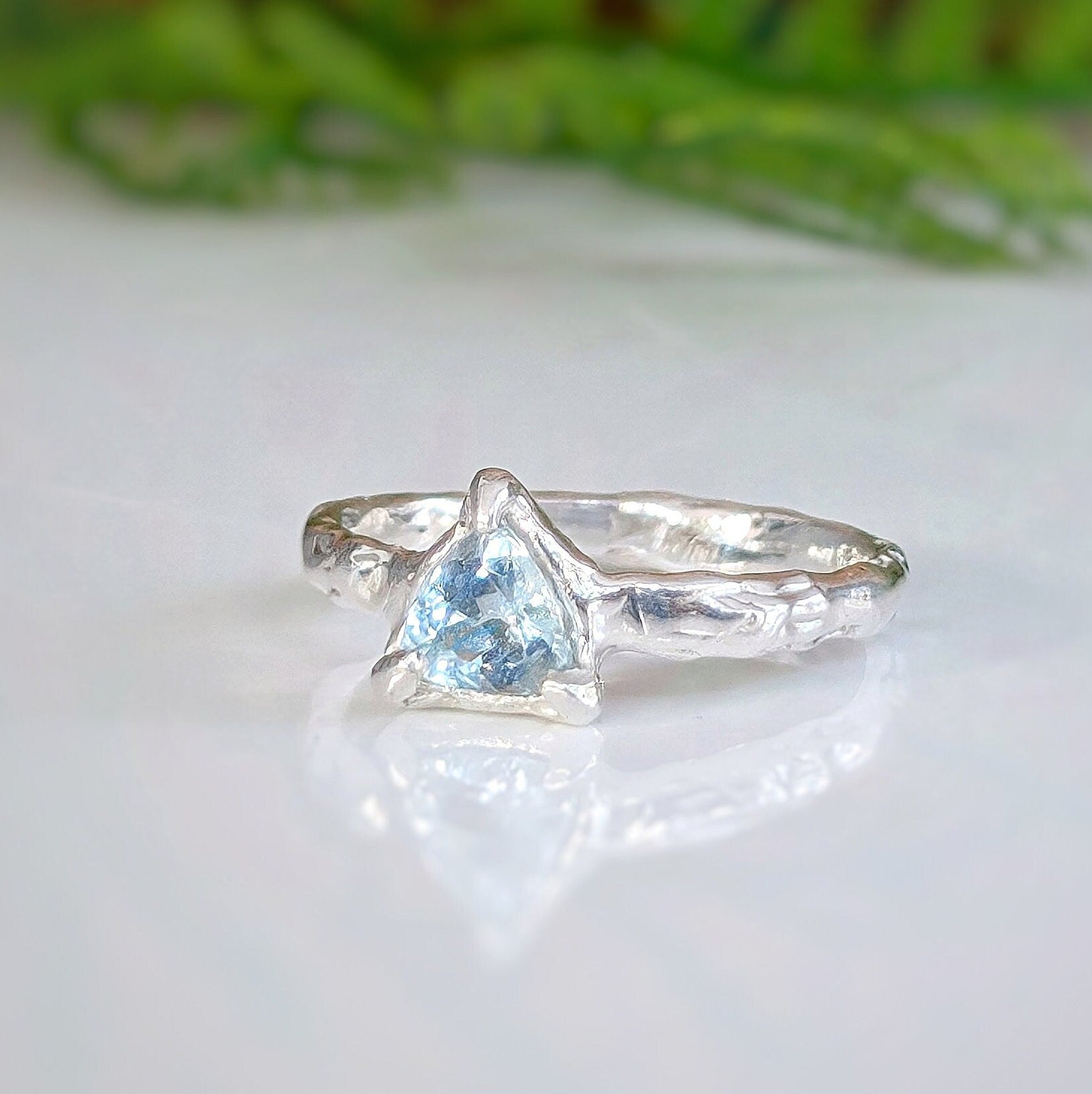 Handcrafted solid silver ring featuring a trilliant shape aquamarine, showcasing a unique organic textured band.