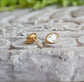 Herkimer diamond stud earrings with gold settings, showcasing raw crystal elegance on a textured stone surface.