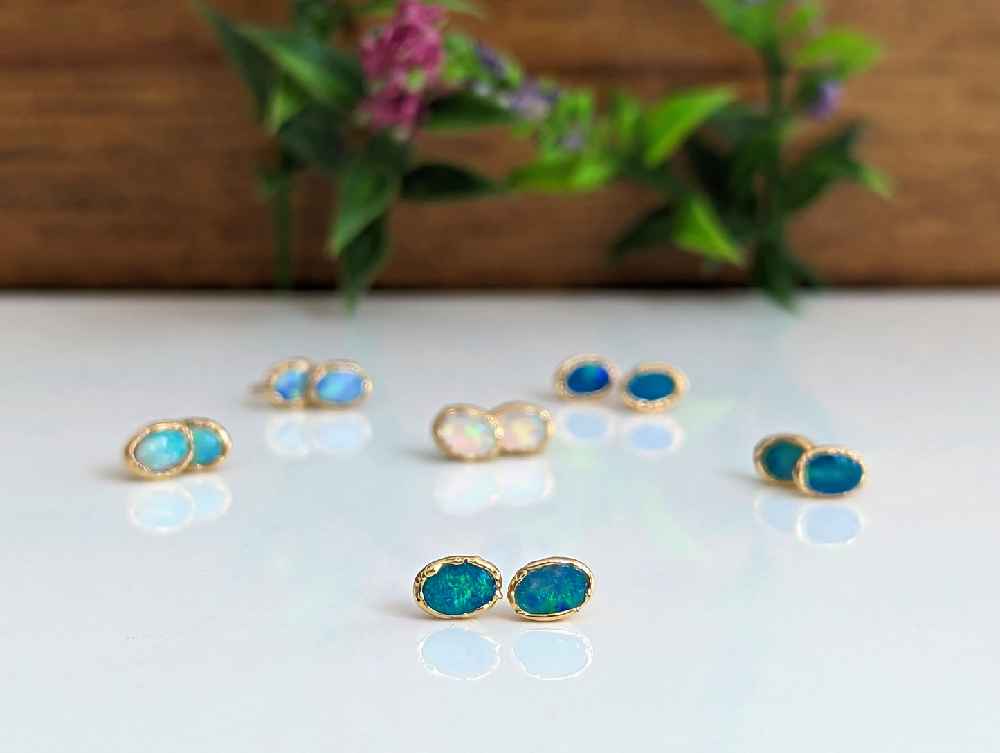 Handcrafted Australian Opal stud earrings on display, showcasing unique colors and 18k Gold accents.